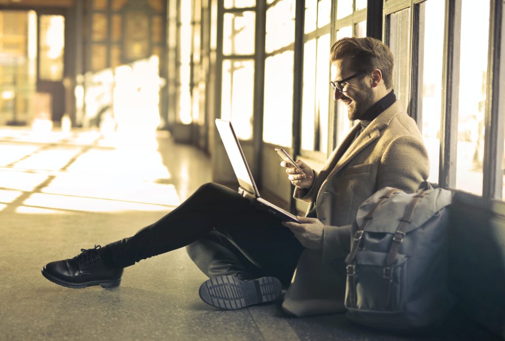 Man viewing phone and laptop